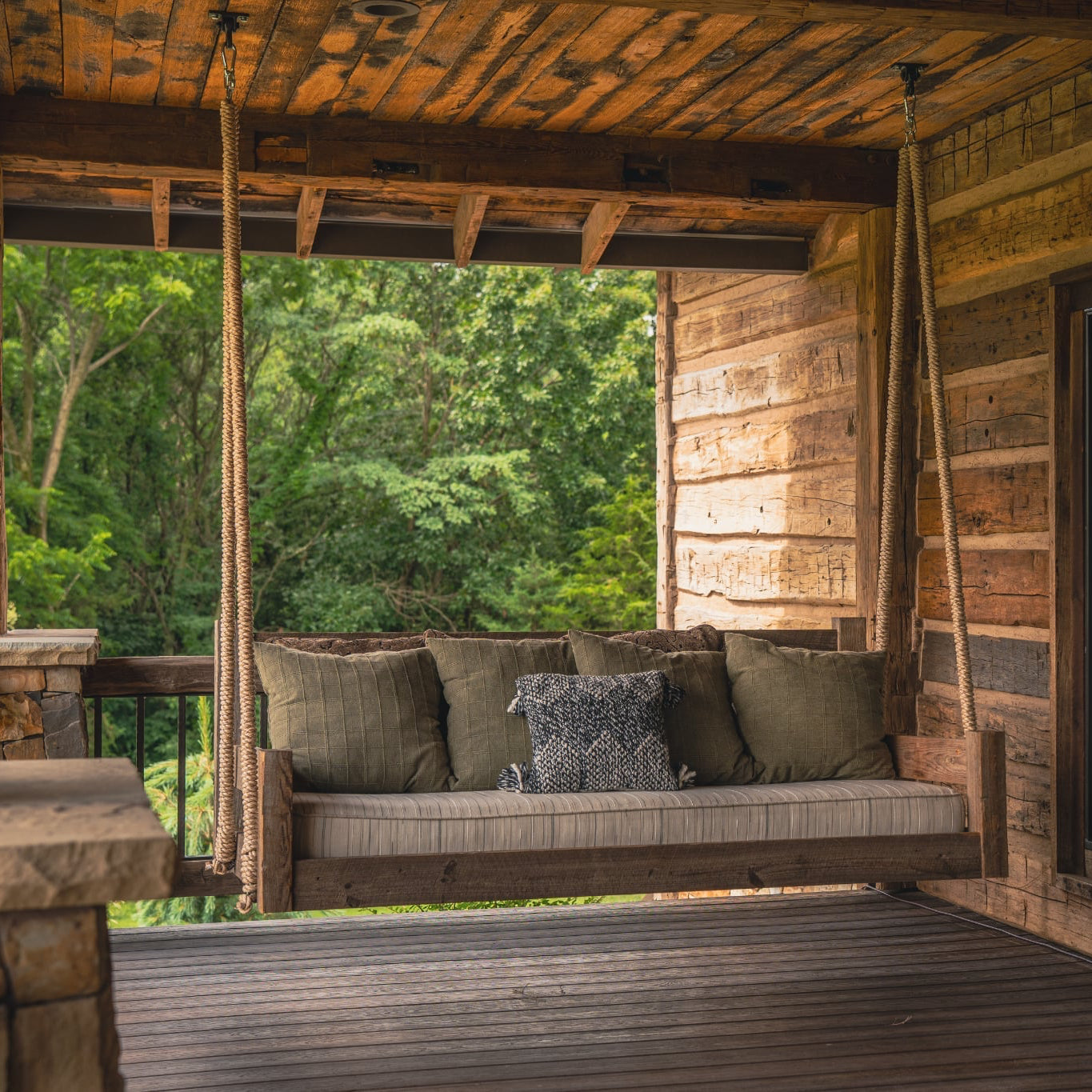 Lakosky reclaimed wood swing bed with rope hanging system and luxury outdoor cushions on rustic porch