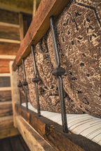 Close-up of a rustic wooden bed with metal backing and perennials patterned fabric.