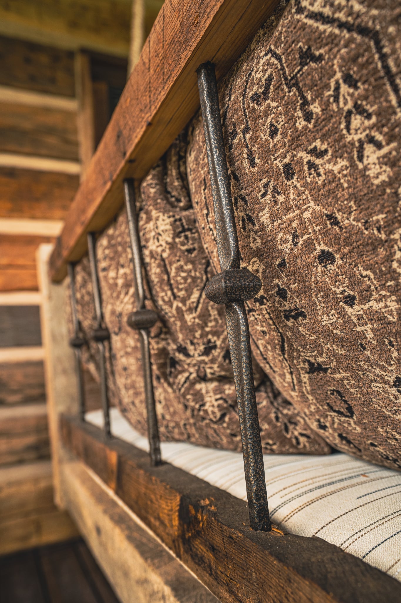 Close-up of a rustic wooden bed with metal backing and perennials patterned fabric.