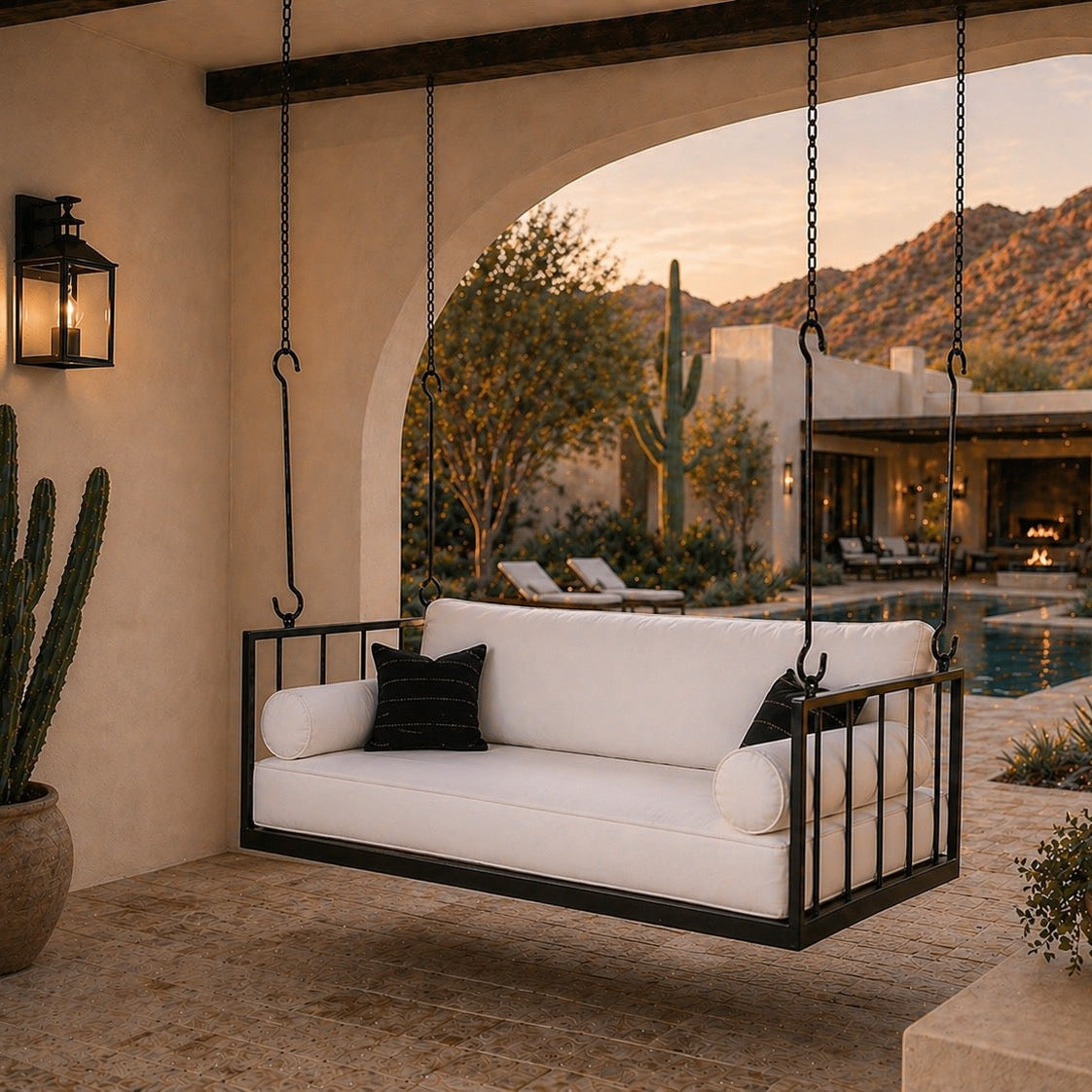 Outdoor swing with white cushions and black metal frame in a desert-themed patio setting.