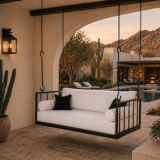 Outdoor swing with white cushions and black metal frame in a desert-themed patio setting.